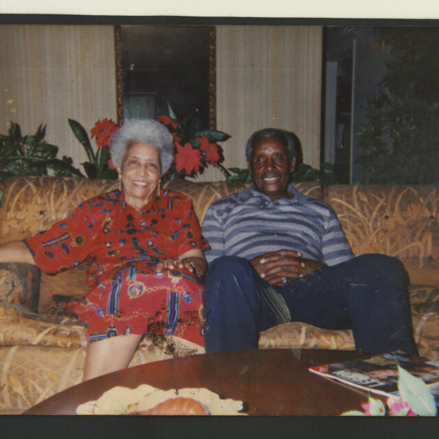 Venus Jones' parents, Bessie and Albert Jones, smiling for a picture while sitting on a couch together.