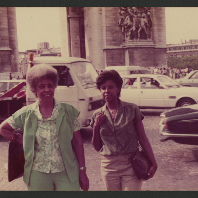 Venus Jones and her mother stand in front of traffic and a large building together for a picture.
