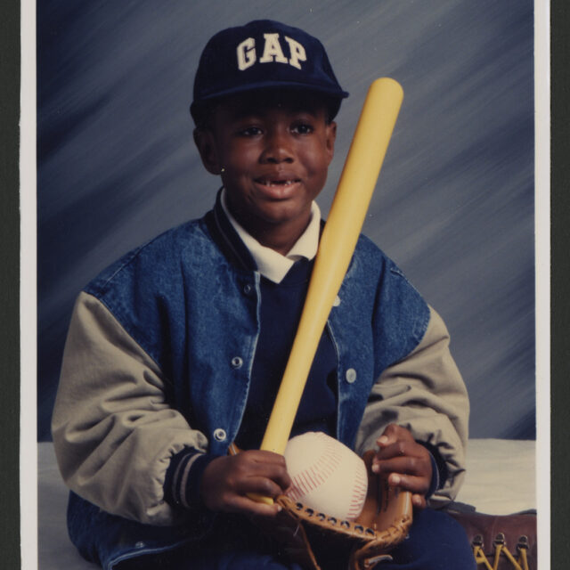 Venus Jones' son, Odell, poses for a picture with a baseball bat, glove, and ball.