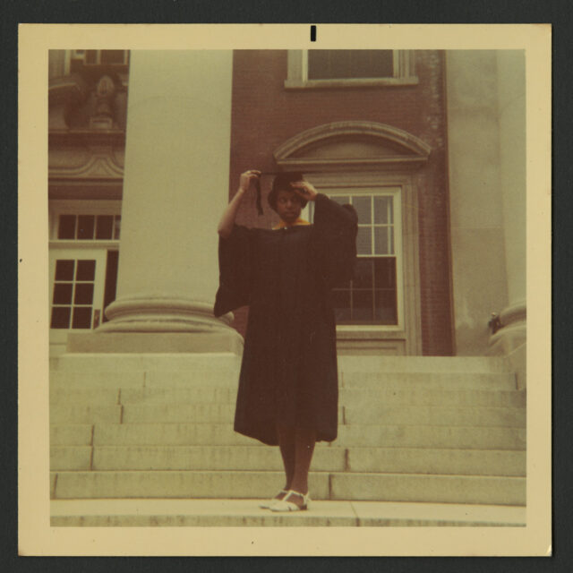 Venus Jones poses on the steps of a building in her cap and gown at her graduation from Mary Washington College.