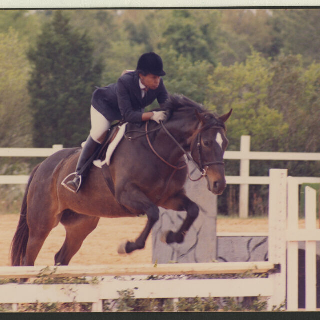 Venus Jones and her horse jump over a fence while competing together.